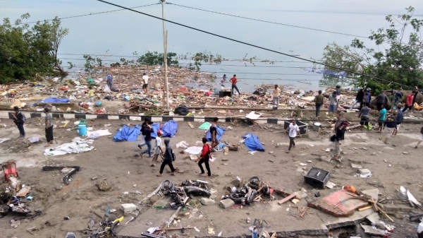 전날 규모 7.5 강진이 발생한 지 몇 시간 만에 쓰나미가 밀어닥친 인도네시아 술라웨시 섬 주도 팔루의 해안가에 29일(현지시간) 사망자들의 시신(파란색 커버)이 놓여 있는 가운데 주민들이 피해 지역을 둘러보고 있다. (사진=AFP/연합뉴스)