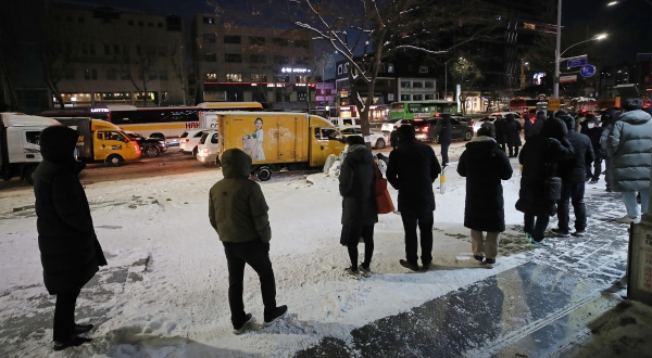 지난 7일 오전 눈 위에서 버스를 기다리는 시민들.(사진=연합뉴스)