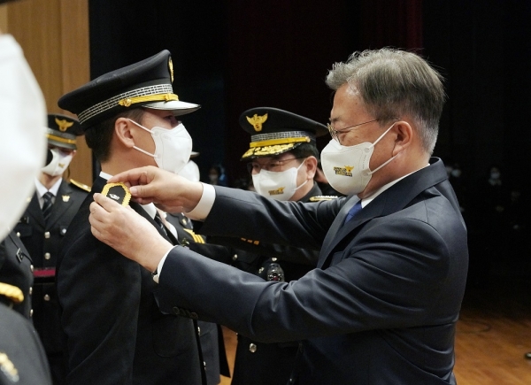 문재인 대통령이 17일 충남 아산 경찰대학에서 열린 2022년 신임경찰 경위·경감 임용식에서 임용자 대표 어깨에 계급장을 부착하고 있다. (사진=연합뉴스)
