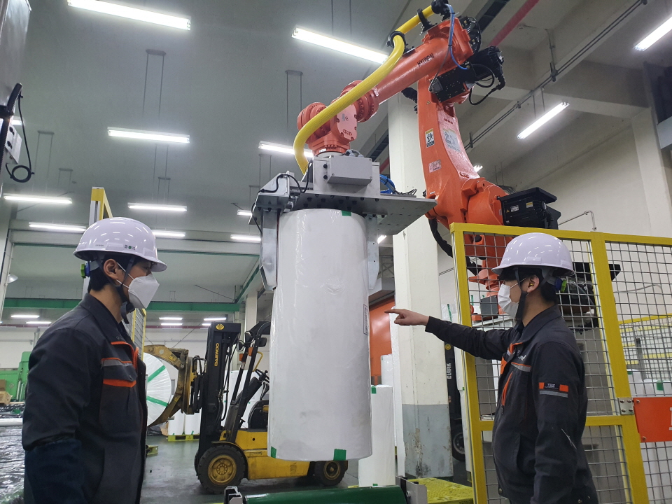 유진한일합섬 의령공장 직원들이 생산라인에 설치된 제조로봇을 가동하는 모습. [사진=유진그룹]