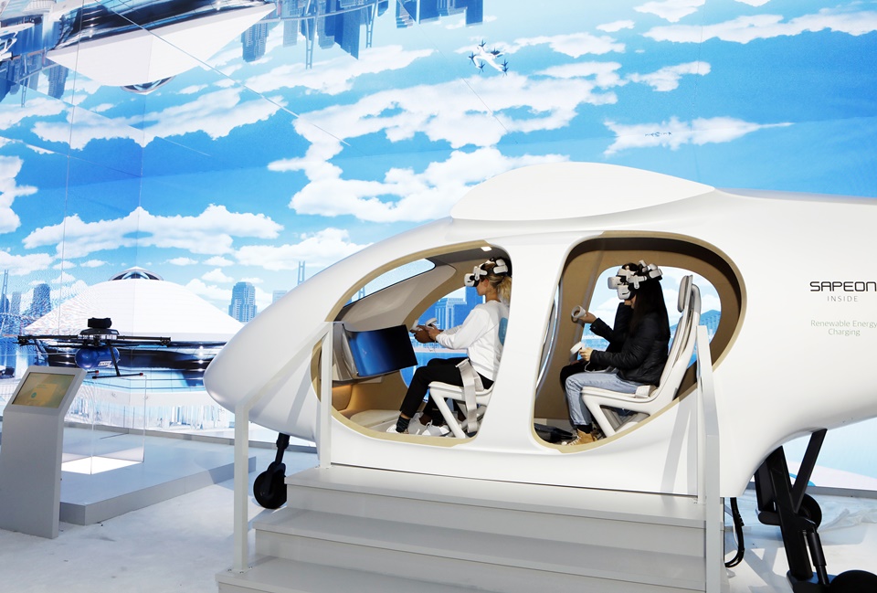 ‘CES 2023’의 SK그룹관을 사전 방문한 관람객들이 SK텔레콤의 도심항공교통(UAM) 모형에 탑승해 운행 체험을 하고 있다.[사진=SK]