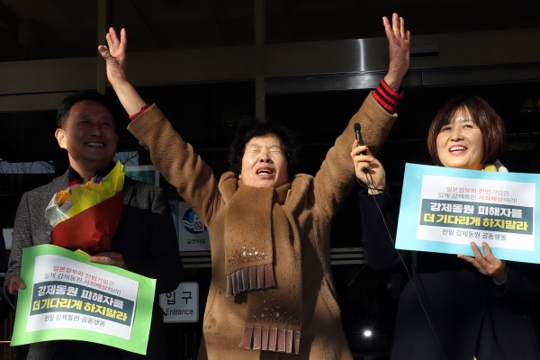 일본 미쓰비시중공업을 상대로 3차 손해배상 청구 소송을 제기한 일제 강제노역 피해자의 유족 이경자 씨(가운데)가 14일 오후 광주 동구 지산동 광주지방법원 청사 앞에서 만세를 외치고 있다. (사진=연합뉴스)