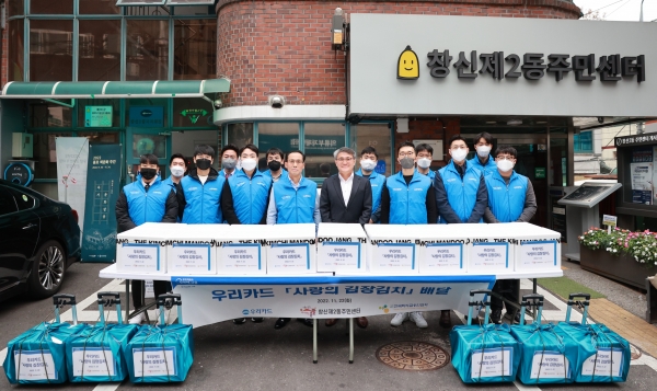 김정기 우리카드 사장(왼쪽 네 번째)과 임직원 및 관계자들이 지난 22일 서울 종로구 창신2동주민센터 앞에서 저소득층을 위한 김장 김치 1톤(t)을 기부하고 기념 촬영을 하고 있다. (사진=우리카드)