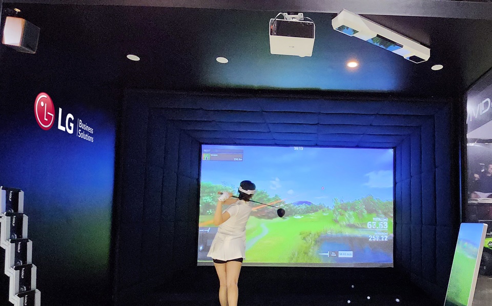 LG전자 모델이 천장에 설치된 프리미엄 상업용 프로젝터 ‘LG 프로빔 레이저 4K’를 활용해 조성한 스크린골프 체험존에서  스크린 골프를 즐기는 모습.[사진=LG전자]