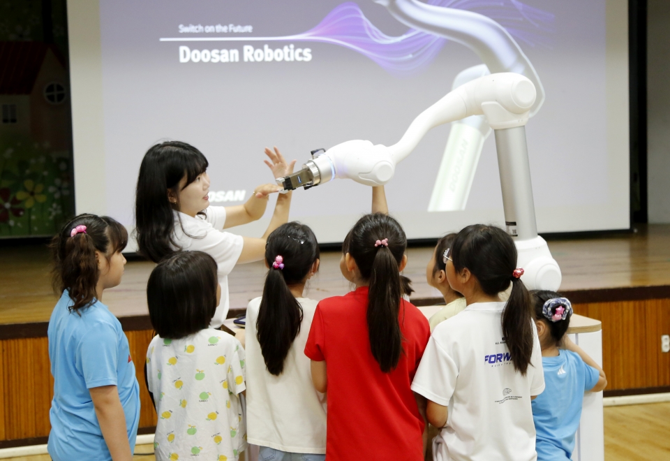 두산로보틱스 임직원이 아이들에게 협동로봇의 개념과 기본적인 작동 과정 등을 교육하고 있다.[사진=두산로보틱스]