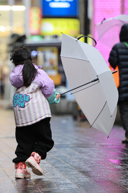 전국 곳곳 비나 눈이 내린 지난 21일 오후 서울 중구 명동거리에서 한 어린이가 바람에 날리는 우산을 잡는 모습. (사진=연합뉴스)